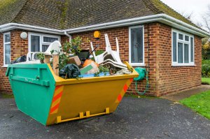 overloaded skip next to a house